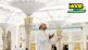 A man holds his hands up in dua, smiling and looking up at the masjid of Rasulullah (S)